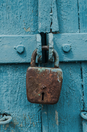 Old iron barn lock on a blue wooden doors. Vertical image.