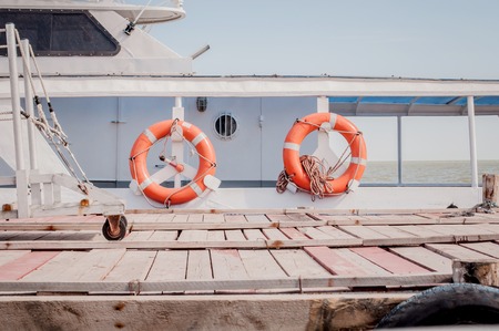 Two red lifebuoys hanging on white touristic boat.
