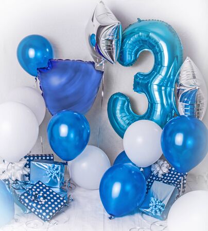 Room decorated for a birthday party with blue, white and silver baloons, large inflatable number 3, presents boxes and ribbons. Photoshooting area at home.の写真素材