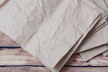 Pile of rumpled kraft paper lying in disorder on a wooden floor