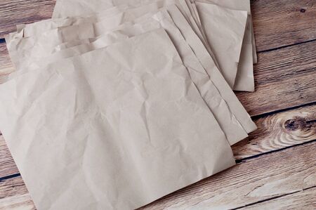 Pile of rumpled kraft paper lying in disorder on a wooden floor