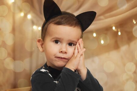 Cute 2 year old boy dressed into black cat costume ready for christmas party.