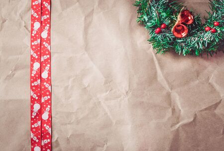 Rumpled kraft paper with red christmas ribbon and festive wreath. Template for a christmas card.