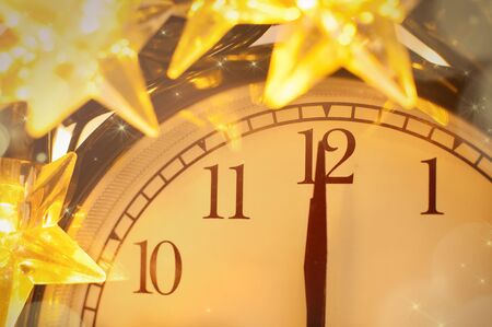 New Year alarm clock face wrapped into festive star garland close up. Midnight. Festive Chritmas background.の写真素材