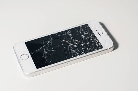 Modern smartphone with seriously broken display screen isolated on white background. Device needs...