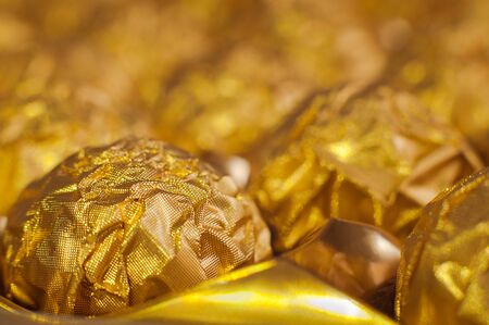 Box of round candies wrapped into golden foil. Macro shot. Luxury food.の写真素材