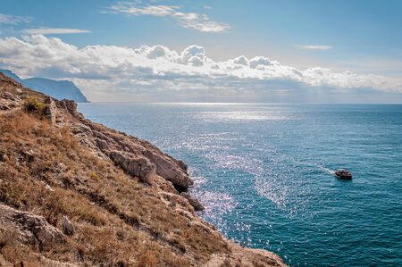 Rocky Coast, mountains, blue sea and sky with white cloudsの写真素材