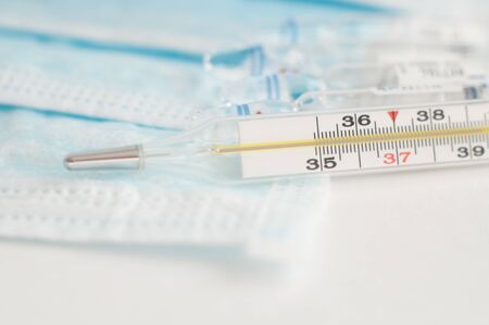 Sterile medical blue masks, vials with vaccine and analogue thermometer on white background. Flu...