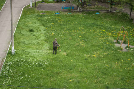 14 May 2020, Voronezh, Russia. A man Working In Garden Cutting Grass With Lawn Mower. Russian housing service.のeditorial素材