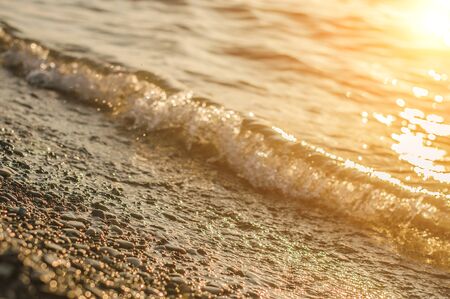 Sea surf on sunset time. Black Sea coast. Pebble washed by sea waves. Selective focus.