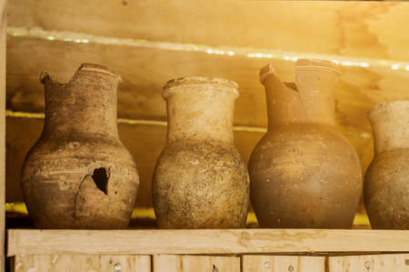 Vintage crocks standing in line in a wooden house.