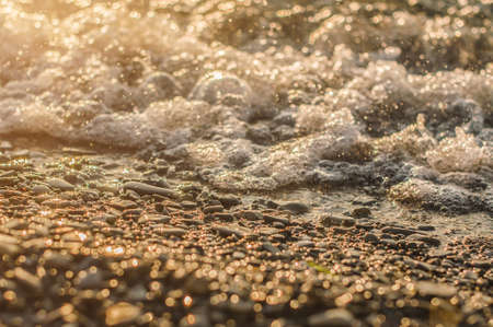 Sea surf on sunset time. Black Sea coast. Pebble washed by sea waves. Selective focus.の写真素材