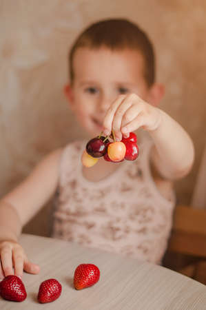 Little boy holding a branch of ripe cherries. Selective focusの写真素材