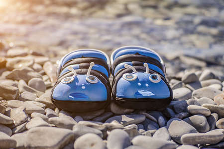 Blue summer flip-flops standing on the rocky shore of the seaの写真素材