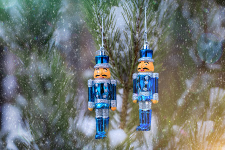 A pair of tin solders hanging on a snowy fir tree in the forest outdors. Christmas toys.