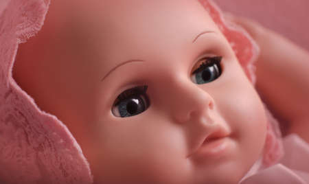 Baby doll toy photodraphed in a newborn style. Wrapped in pink woolen fabric and lace capの写真素材