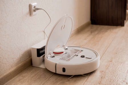 White robot vacuum cleaner on the floor in the interior. Charge on a doc stationの写真素材