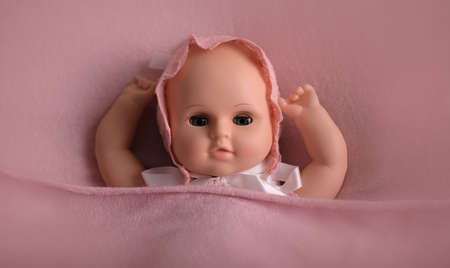 Baby doll toy photodraphed in a newborn style. Wrapped in pink woolen fabric and lace capの写真素材