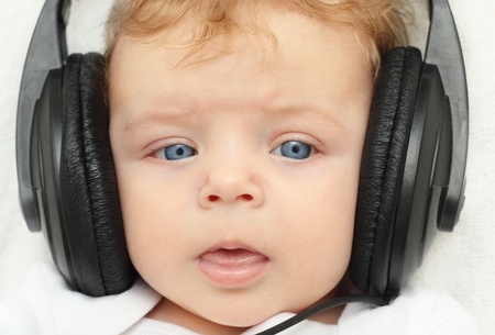 Happy baby boy 3 month old in earphones babblingの写真素材