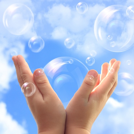 Soap bubbles in child hands against blue sky.の写真素材