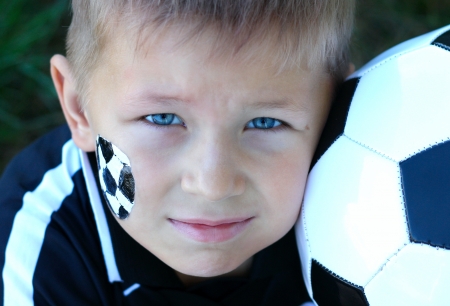 A young boy with painted face and soccer ball の写真素材