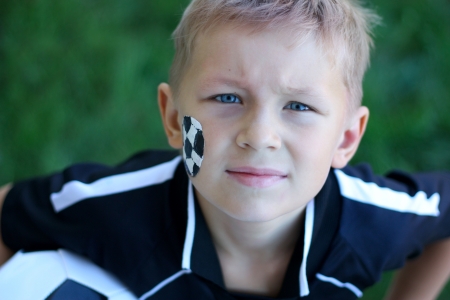 A young boy with painted face and soccer ball の写真素材