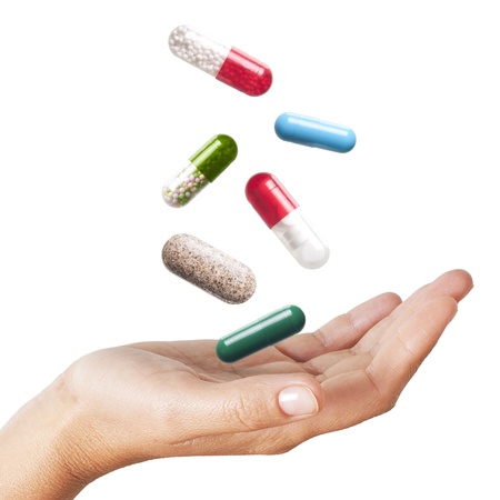 Woman hand with falling pills isolated on white background の写真素材