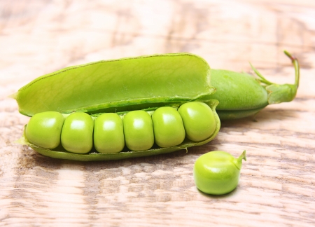 Pod of green peas on wooden backgroundの写真素材