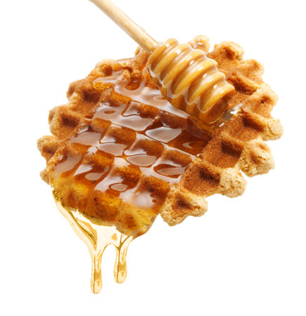 Honey drip from wooden dipper on waffle isolated on white backgroundの写真素材