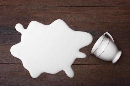 White cup and milk splash on wooden background.の写真素材