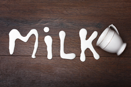 White cup and milk splash on wooden background.の写真素材