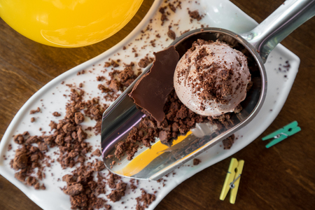 White plate of chocolate ice cream scoops sprinkled with chocolate on wooden tableの写真素材