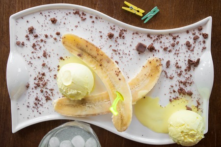 Fruit ice cream with fresh banana sprinkled with chocolate on white plateの写真素材