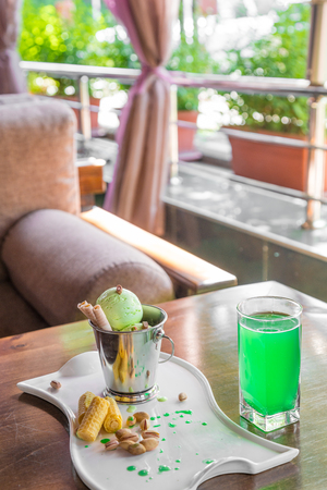 A bucket cup of pistachio ice cream topped with corn cones on white table in on the summer verandaの写真素材