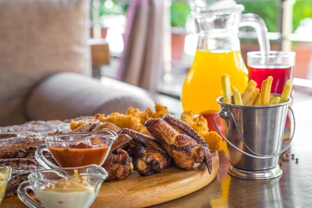 Grilled beef steak and Assorted delicious grilled meat with french fries and cool drinks on the table of the summer verandaの写真素材