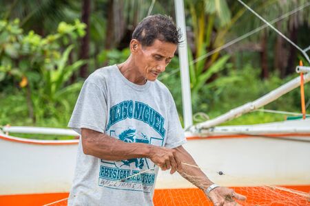 Old fishermen are repairing fishing nets at El Nido, Palawan, Philippines. August 2018.