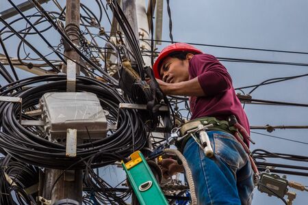 Indonesian electrician repair workers are to fix the line of network cable and wire on electric pole. Jakarta, Indonesia. Jule 2018のeditorial素材