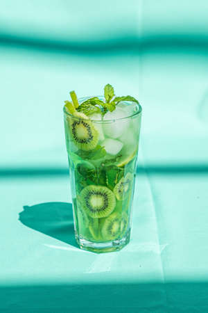 Kiwi lime drink with mint and ice in glass close up on turquoise background.の写真素材