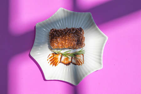 Piece of chocolate Brownie Cake with icing on plate on a purple abstract background.