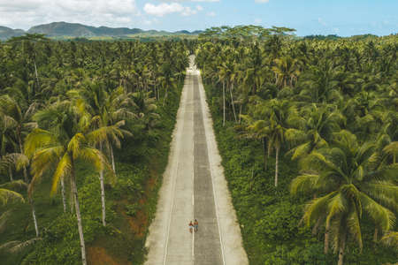 Aerial drone view a Couple on the road with palm trees in Siargao, Philippines.の写真素材