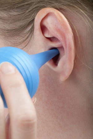 woman cleaning her ear with a bulb syringe