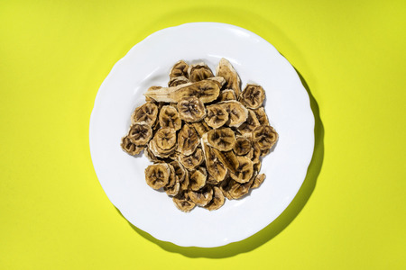 Sun-dried (dried), banana slices in a plate on a yellow backgroundの写真素材