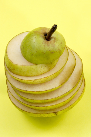 Cut into slices of ripe pear on a yellow backgroundの写真素材