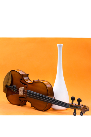 Still life with violin and white vase on an orange backgroundの写真素材