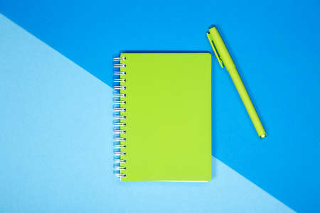Green notebook and pen on a colored backgroundの写真素材