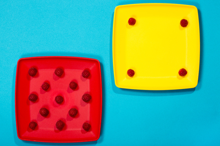 Berries of ripe raspberries on colored plates on a blue backgroundの写真素材