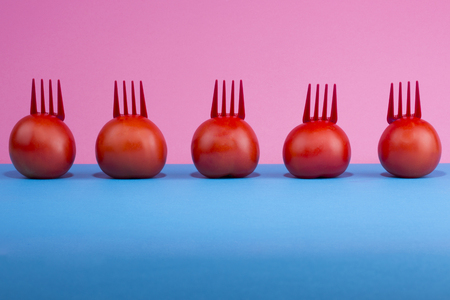 Abstract still life with tomatoes and forks on a colored backgroundの写真素材