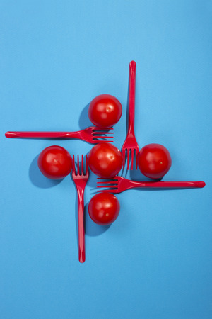 Abstract still life with tomatoes and forks on a blue background
