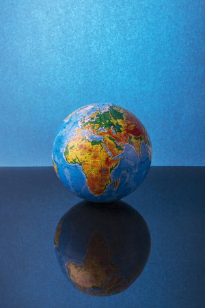 Globe on a reflective surface on a blue backgroundのeditorial素材