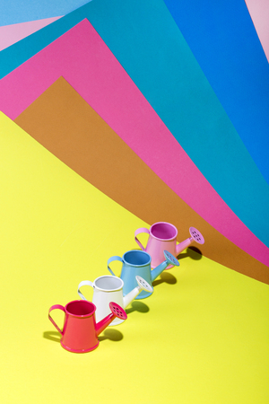 Four small watering cans on a colored backgroundの写真素材